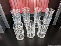 Eleven clear textured tall glasses stacked in two groups showing geometric square and circle patterns in clear glass.