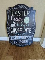 Photo of a black decorative Easter sign with pastel colored chalkboard style lettering and images.