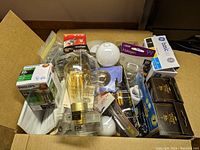 Two boxes of assorted lightbulbs on table with various brands and types visible