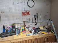 Zoomed out view showing more tools laid out on workbench including additional small hand tools and hardware containers
