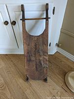 Front view of the handmade wooden sled showing carved decorative pattern and overall shape.