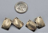 Four rectangular 14K white gold cufflink faces with engraved lines and black enamel corner accents, shown with a US quarter for scale