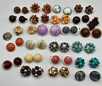24 pairs of vintage clip-on earrings arranged in rows showing variety of colors and materials