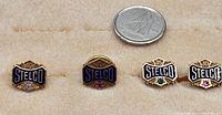 Four gold Stelco service pins on beige background next to Canadian quarter
