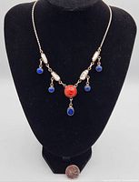 Front view of the necklace on a display bust showing the arrangement of stones and pearls.