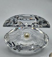 Front view of clear faceted crystal clam shell dish with pearl inside.