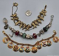 Top view of all three charm bracelets laid flat with a quarter coin for size reference.