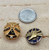 Both pins side by side next to a dime for scale