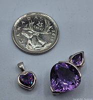 Two purple stone sterling silver pendants side-by-side with Canadian quarter for size reference.