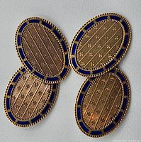 Top view of both cufflink faces showing oval shape, blue enamel border, and engraved pattern.