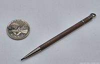 Full view of the vintage mechanical pencil with a Canadian quarter for size comparison, showing its length and textured barrel.