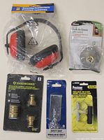 Front view of hearing protection headphones, dusk-to-dawn light socket control, brass quick disconnect hose couplings, safety hasp, and hose repair kit in original packaging