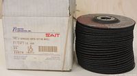 Box labeled 'United Abrasives, Inc. SAIT' with quantity 25, 5x3/32x7/8, part number 22070 next to the stack of black abrasive cut-off wheels.