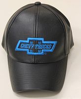 Front view of an unworn black leather-like hat with blue Chevy Trucks logo embroidered on front.