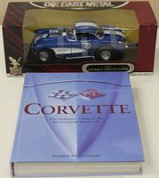 Front view of diecast model car in packaging and book laying flat with cover readable.