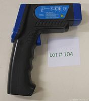 Side view of the handheld infrared thermometer showing the pistol grip handle and the label with brand and safety certifications.