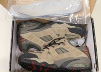 Pair of Kodiak steel toe safety boots inside box with plastic bag containing rubber insoles on top.