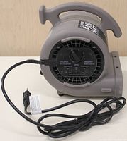 Side view of the Lasko Super Fan Max air mover showing the control panel with dial, circuit breaker, and two 110V auxiliary outlets. Long power cord coiled in front.