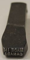 Close-up of stamp face with raised text 'MADE IN CANADA' in reverse for imprinting.