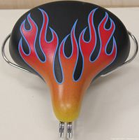 Front view of the bicycle seat showing flame graphics and chrome suspension springs underneath.