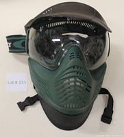 Front view of green V-Force paintball mask with clear lens, black visor, and ventilation holes.