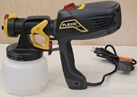 Side view of Wagner Flexio 570 paint sprayer with container and power cord displaying trigger, grip and branding.