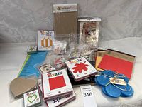 Wide view of crafting scrapbooking lot showing Sizzix dies, paper sheets, clear stamps, and embellishments on display