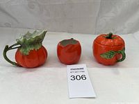 Three ceramic pumpkin-themed kitchen decor items: creamer pitcher, small container, covered jar
