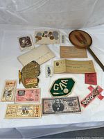 Full view of all items arranged on white cloth including cards, tickets, ticket stubs, a fan, paddle, and cloth patch.