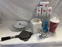 Full view of all items including plates, griddle pan, ceramic vase, blue decanter, squirrel nutcracker, corkscrew boxes, and red cups