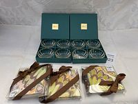 Full lot of eight Mikasa Sunbeam Gold glass condiment bowls in two green Mikasa boxes, with three sets of turkey-themed fabric napkin rings with brown ribbons in front.