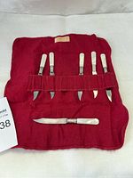 Set of six vintage band knives with mother of pearl handles and sterling silver bands in a red fabric holder.