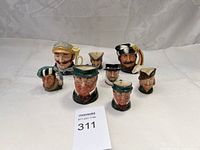 Eight small Royal Doulton character mugs displayed together, showing variety of painted faces and hats.