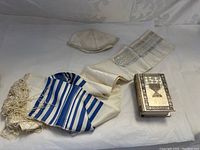 Wide shot of Bible, prayer scarf, and kippah on white surface