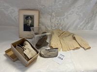 Overview of the vintage baby items including baby shoes in box, baby booties in display box, baby sweater, and framed photograph.