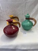 Three vintage ceramic pitchers with wooden handles on white background, shown from front