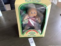 Front view of the 1984 Cabbage Patch Kid doll inside its original packaging showing the doll's face, outfit, and box design.