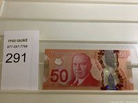 Front side of Canadian $50 bank note in plastic sleeve showing portrait and holographic elements.