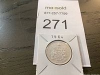 Front and back images of the 1964 Canadian half dollar coin in a coin holder, showing the date and Canadian coat of arms.