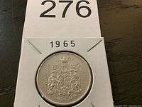 Photo showing reverse side of the 1965 Canadian half dollar coin with Canadian coat of arms and denomination.