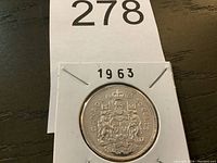 Front side of the 1963 Canadian half dollar coin in a cardboard holder with the year visible on the top.