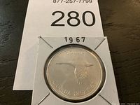 Obverse side of the coin showing a flying goose with inscriptions 'DOLLAR' and 'CANADA 1867-1967'.