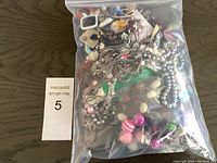 Bag containing mixed estate costume jewellery including necklaces, bracelets, and earrings visible in various colors and materials