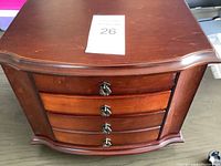 Closed wooden jewelry box with 4 curved drawers and metal handles