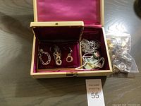 Photo of two jewelry boxes with assorted costume jewelry pieces inside and loose pieces in plastic bag