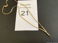 Full view of gold-tone necklace with V-shaped rhinestone pendant on black background with MaxSold auction tag.