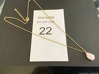 Full view of gold-tone chain necklace with pink stone pendant, showing adjustable length and lobster clasp.