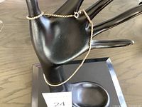 Necklace displayed on a black mannequin hand showing the full chain and clasp design.