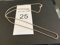 Full view of silver rope chain necklace laid flat with auction number card beneath.