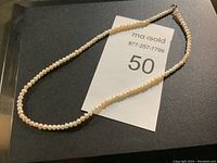 Photo showing full length of pearl necklace laid flat.